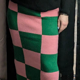 Person wearing a pink and green checkered skirt with a black top