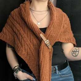 Person wearing a rust knit shawl over a black top and jeans