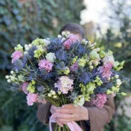 Handheld bouquet of pink, white, and blue flowers tied with a ribbon