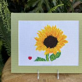 Framed sunflower cross-stitch on a stand