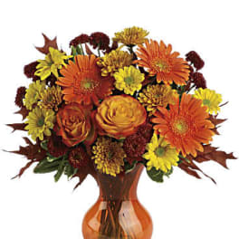 Orange and yellow mixed bouquet in an amber glass vase