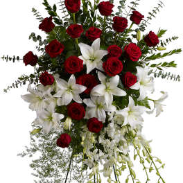 Standing floral spray of red roses and white lilies on an easel