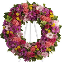 Heart-shaped floral wreath on a white easel with pink, purple, and yellow flowers