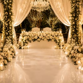 White floral wedding stage with draped fabric and candles