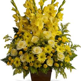 Yellow floral arrangement in a brown urn vase