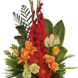Tropical flower arrangement with red, orange, and green blooms in a wooden container