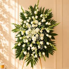 White floral standing spray on an easel with palm leaves