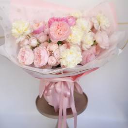 Round bouquet of pale pink and cream roses and peonies in a pink hatbox with ribbon