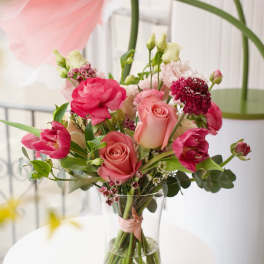 Pink and coral bouquet of roses and tulips in a clear glass vase