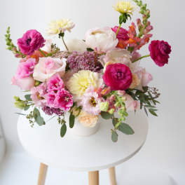 Mixed bouquet of pink, white, and yellow flowers in a white vase