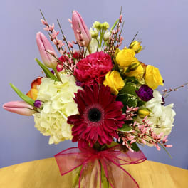 Mixed bouquet in a glass vase with pink, yellow, white, and red flowers
