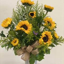 Sunflower arrangement in a tall silver vase with a burlap bow