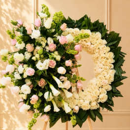 Large floral wreath on an easel with cream, pink, and green flowers