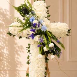 Large white floral cross on an easel with blue and purple accents