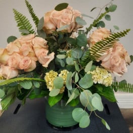 Peach roses and pale yellow hydrangeas in a green vase