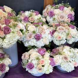 Clusters of pastel roses and white hydrangeas arranged in round bouquets