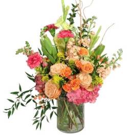 Mixed bouquet of peach, pink, and orange flowers in a glass vase
