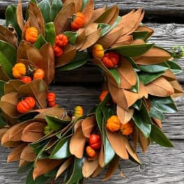 Autumn wreath with green and brown leaves and small orange pumpkins