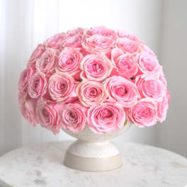 Round bouquet of pink roses in a white pedestal vase