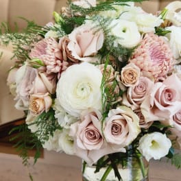 Bouquet of blush roses, white ranunculus, and pink chrysanthemums in a glass vase
