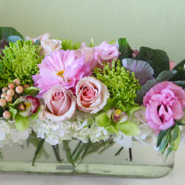 Pink and green floral arrangement in a clear rectangular vase