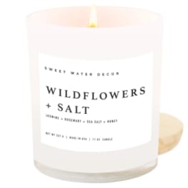 Lit white candle in a glass jar labeled Wildflowers + Salt