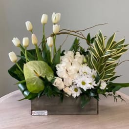 White tulips, roses, and daisies arranged in a wooden box
