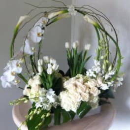 White floral arrangement with orchids and roses in a circular frame
