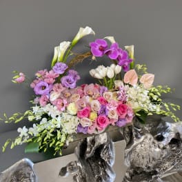 Large floral arrangement with pink, purple, and white blooms in a decorative container