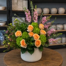 Peach roses and pink snapdragons in a white textured vase