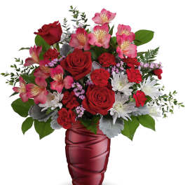 Red roses and pink alstroemeria in a red glass vase