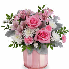 Pink roses and mixed blooms arranged in a pink glass vase