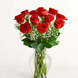 Red roses arranged in a clear glass vase with white baby's breath