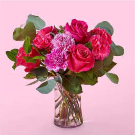 Pink roses and carnations in a clear glass vase