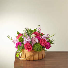 Pink and magenta flower arrangement in a woven basket