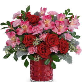 Red roses and pink flowers in a red heart-pattern vase