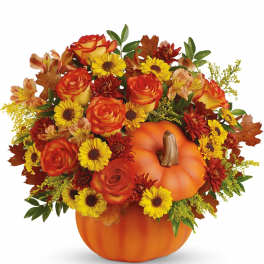 Autumn floral arrangement in a pumpkin container with orange roses and yellow daisies