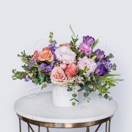 Pastel floral arrangement in a white vase with pink and purple blooms