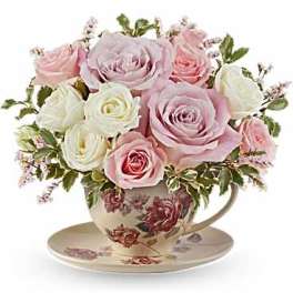 Pink and white roses arranged in a floral teacup