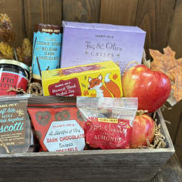Gift basket with apples, snacks, tea, and autumn leaves