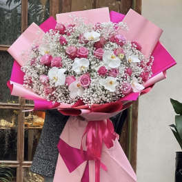 Large bouquet of pink roses and white orchids wrapped in pink paper