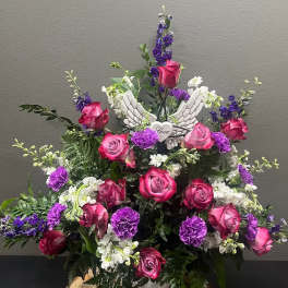 Pink and purple rose arrangement with white flowers and angel wings