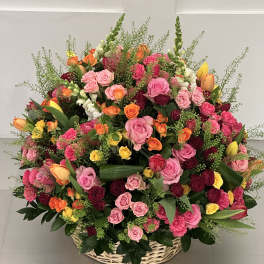 Large basket arrangement of pink, red, orange, and yellow roses