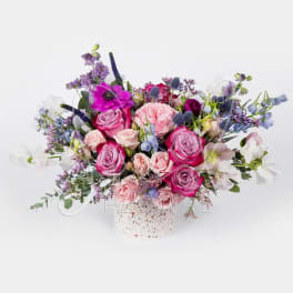 Pink and purple rose bouquet in a speckled white vase