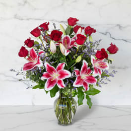 Red roses and pink lilies in a clear glass vase