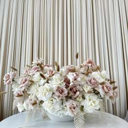Large arrangement of pale pink and white roses in a white bowl vase