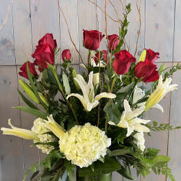 Red roses and white lilies in a tall glass vase with greenery