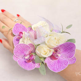Pink orchid corsage with white roses worn on a wrist