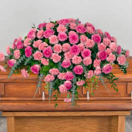 Pink roses and carnations arranged on a wooden casket