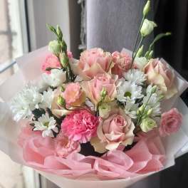 Pink and white bouquet of roses, carnations, and daisies wrapped in pink paper